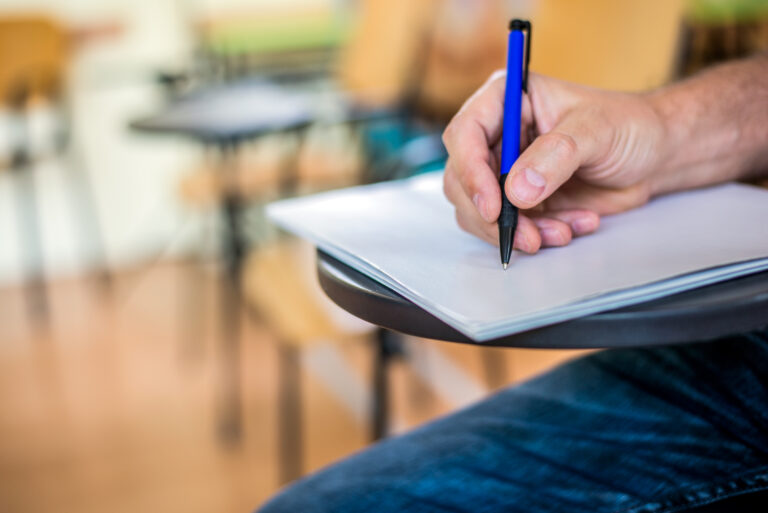 A man is writing/signing on a paper. Focused on a hand with pen