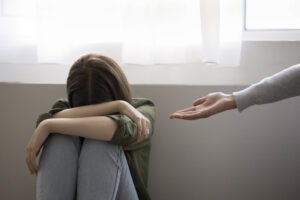 Adult woman giving helping hand to crying teenager girl