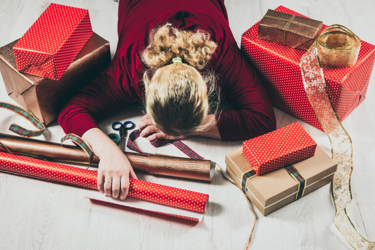 Top down view of unrecognizable woman housewife tired of wrapping Christmas presents and lying down. Seasonal holidays depression concept.